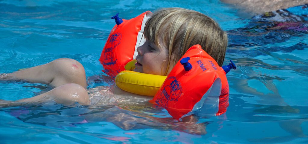 Kind liegt im Wasser mit Schwimmflügel